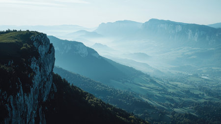 Experience the breathtaking beauty of a misty mountain landscape, showcasing serene valleys and majestic peaks under a gentle blue sky, perfect for nature lovers.の素材
