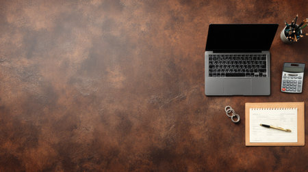 A stylish and modern workspace featuring a laptop, notebook, calculator, and pen on a rustic brown desk, ideal for business and productivity needs.の素材