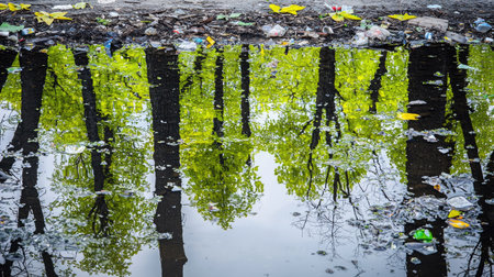 A serene view of lush green trees reflected in calm water, highlighting environmental issues with visible debris. Ideal for nature and pollution themes.の素材