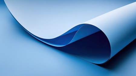 Close-up view of a soft blue paper curl creating an elegant wave effect. The minimalist design showcases subtle shadows and smooth textures, ideal for creative projects.の素材