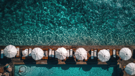 A captivating aerial view showcasing a tropical poolside scene with white umbrellas, inviting sun loungers, and crystal clear turquoise water, perfect for relaxation.の素材