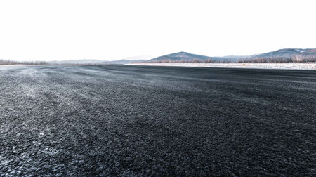 A smooth asphalt road stretches into the distance, flanked by mountains under a clear sky. This image captures a sense of solitude and openness in nature.の素材