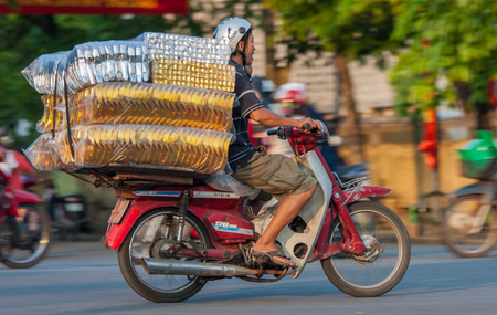Hanoi, Vietnam - since cars are expensive and the traffic crazy, in Vietnam scooters are used to transport goods in place of cars. Here in particular a scooter overloaded of goodsのeditorial素材