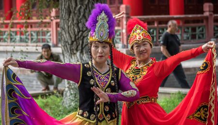 Urumqi, China - capital of the Xinjiang Uygur Autonomous Region, Urumqi is home of the colorful and welcoming Uyghur ethnic group. Here in particular two women dancing in People's Parkのeditorial素材