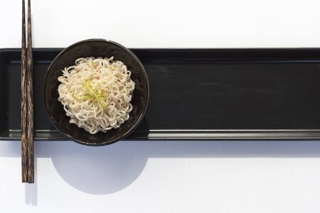 Noodle put on the middle of the black tray with white backgroundの写真素材