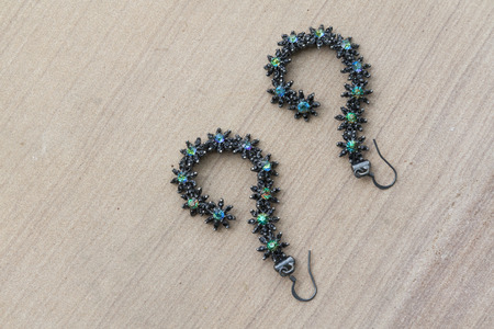 Beautiful flowers earring with a question mark shape on the stone floorの写真素材