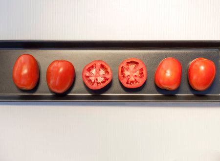 Healthy Organic tomatoes arrangement on black tray showing two slices of tomato fresh and juicyの写真素材