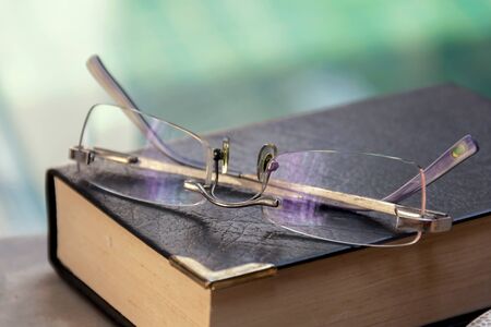 Eye glasses on the black cover book blur swimming pool backgroundの写真素材