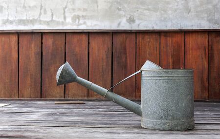 Metal watering pot with red wood wall backgroundの写真素材
