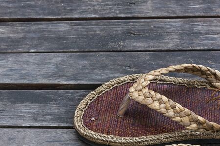 Handmade natural material sandals on with space on wood floor backgroundの写真素材