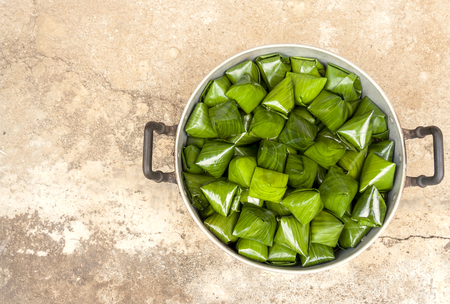Traditional thai sweet wrapped with banana leaf with space on cement floorの写真素材