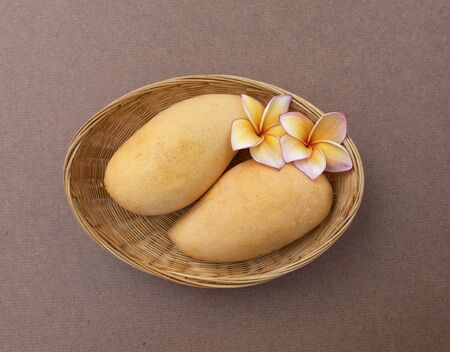 Two yellow thai mango in the basket with plumeria flowerの写真素材