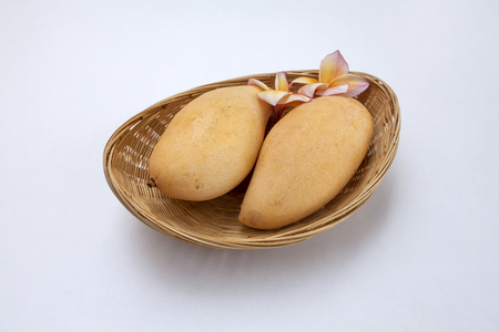Two yellow mango in the basket on white backgroundの写真素材