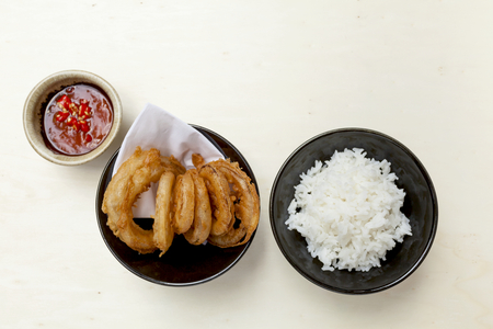 Deep fried onion with rice and red chili sauce with space on wood tableの写真素材