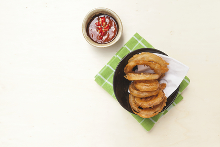 Golden onion ring on green napkin with chili sauce on wood tableの写真素材