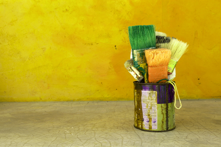 Yellow retro tone the old paint brush in rusty tin with space on cement wallの写真素材