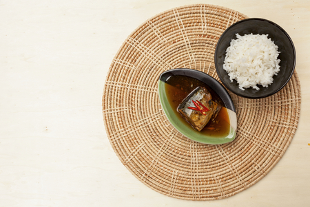 Saba fish in teriyaki sauce and rice on rattan placemats with space on wood backgroundの写真素材