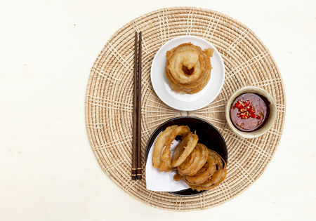 The onion ring set with red chili sauce on rattan placemat with space on backgroundの写真素材