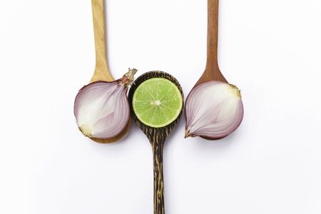 Fresh thai lime and red onion on wooden spoon with space on white background center styleの写真素材