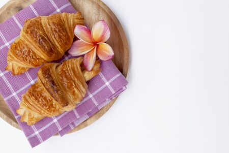 Golden brown croissant on wooden plate with space on white backgroundの写真素材