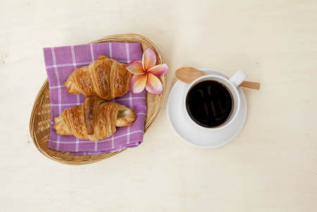 Croissant serve in basket with black coffee on wood backgroundの写真素材
