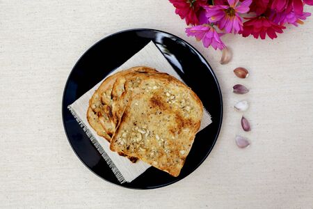 Garlic bread on black plate with flower on backgroundの写真素材