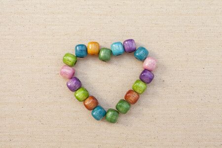 Wooden beads in heart shape on fabric backgroundの写真素材