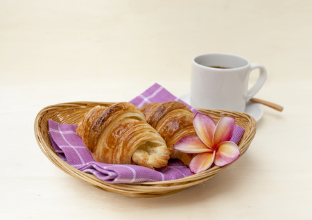 Closeup Golden brown croissant on basket with plulmeria flower and coffee horizontal styleの写真素材
