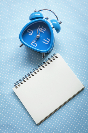 Blue clock and blank notebookの写真素材