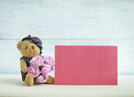 Pink card and Teddy bear holding pink paper rose flowersの写真素材