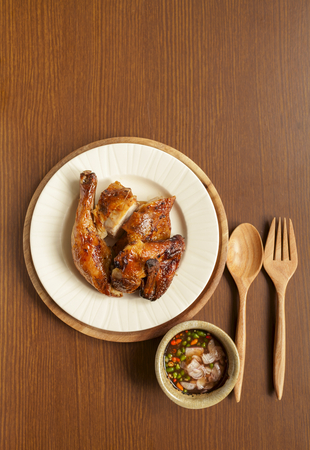 Grilled chicken with thai spicy sauce with space on wood table backgroundの写真素材