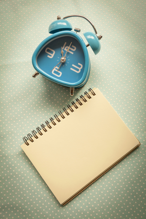 Vintage tone style blue clock with blank notebookの写真素材