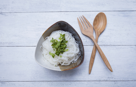 Rice noodle in ceramic bowl with wooden fork and spoonの写真素材