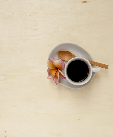 Plumeria flower on morning black coffee cup with space on wooden tableの写真素材