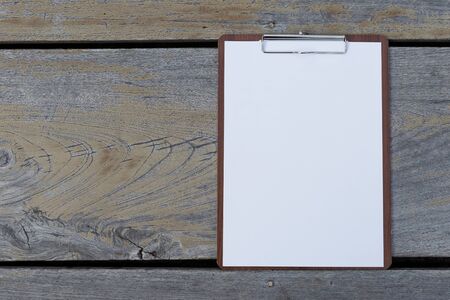 White paper on clipboard on wooden floor background