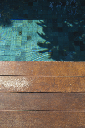 Swimming pool under the trees shade with space on wooden floorの写真素材