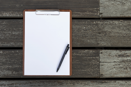 Blank white paper sheet on clipboard with black pen on wood floor backgroundの写真素材
