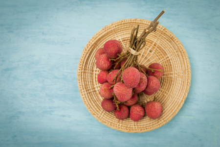 Fresh red lychee from Thailand on rattan tray with space on blue backgroundの写真素材