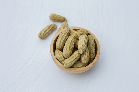 Steamed peanut in wooden bowl on white texture background