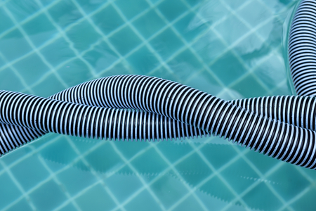 Closeup swimming pool vacumm hose twist on water surface backgroundの写真素材