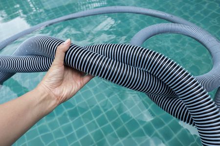 Girl hand holding twisted swimming pool vacuume hose