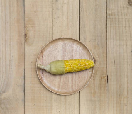 Steam sweet corn on wooden round tray with space on wood backgroundの写真素材