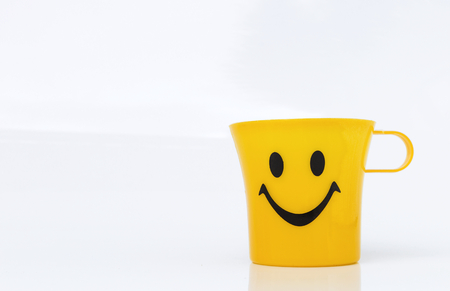 Happy smile on plastic yellow cup on white backgroundの写真素材