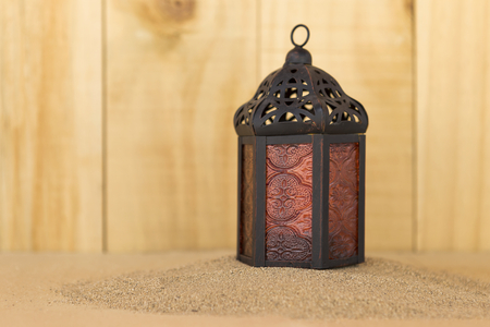Metal lantern on sand with space on wood backgroundの写真素材
