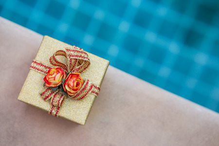 Present on swimming pool, gold gift boxの写真素材