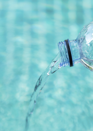Closeup pouring water from plastic bottle with blue water backgroundの写真素材