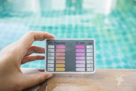 Girl hand holding water testing test kit on swimming pool edgeの写真素材