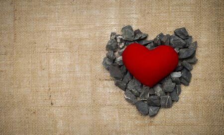 Red heart on grey stone in heart shape on hessian texture backgroundの写真素材