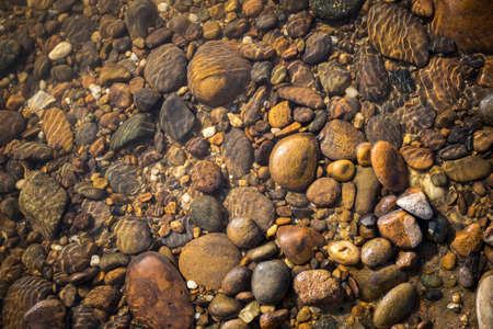 Natural round stone under clear river water background