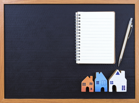 Home buyer, Blank notebook and wooden miniature house over black backgroundの写真素材